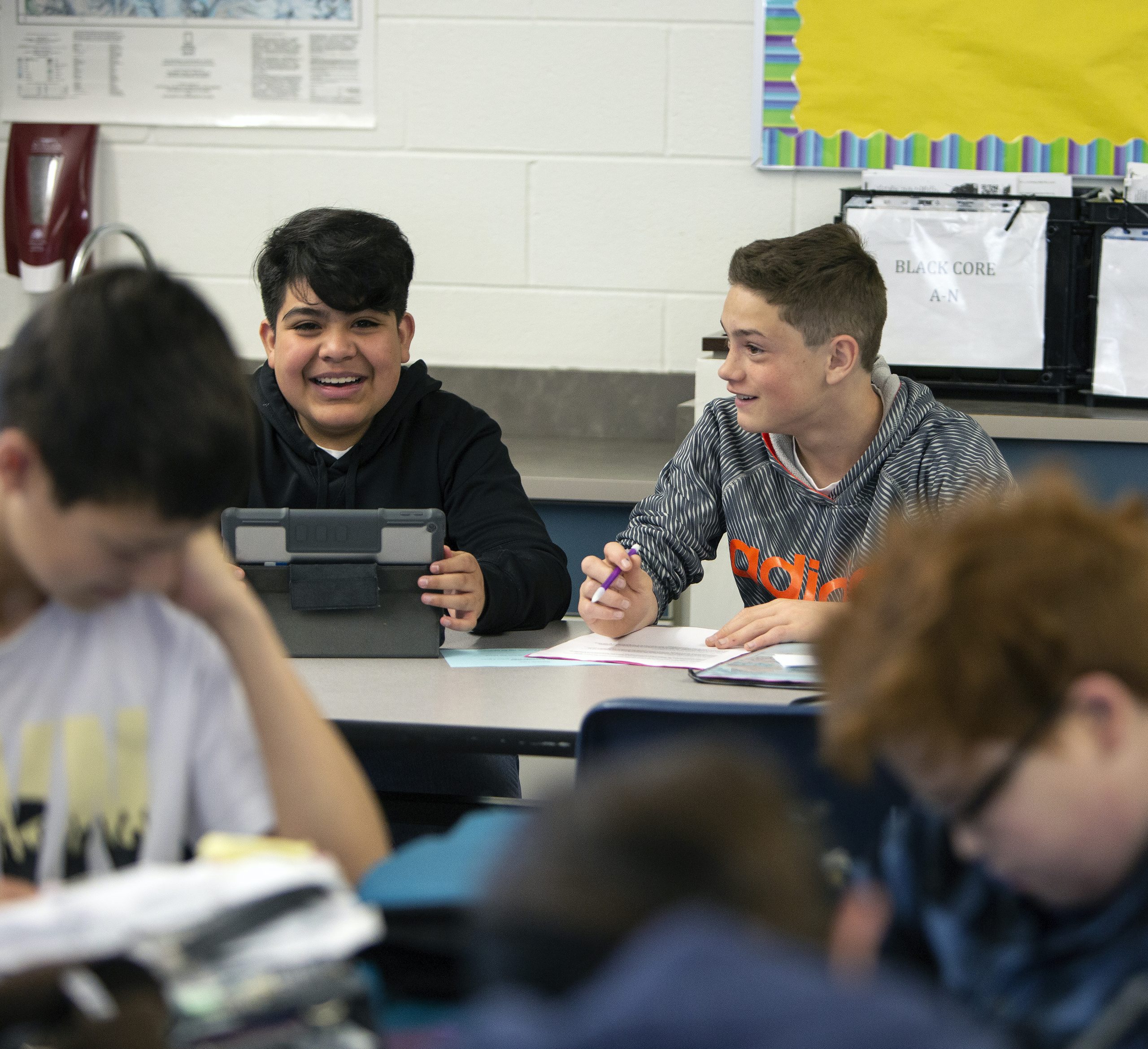 Two boys smiling during class with iPad