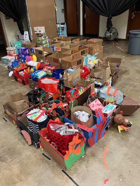 A collection of creatively decorated cardboard boxes filled with various items, arranged on a floor in a room.