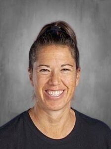Smiling woman with a ponytail, wearing a black shirt, against a gray background.