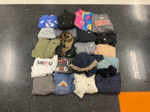 A neatly arranged display of various folded clothing items, including sweatshirts, jackets, and hoodies.